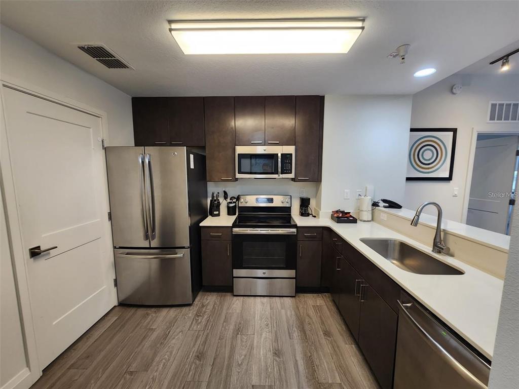 A kitchen features dark wood cabinets, stainless steel appliances, and white countertops — 14501 GROVE RESORT AVENUE UNIT 3401, WINTER GARDEN, FL