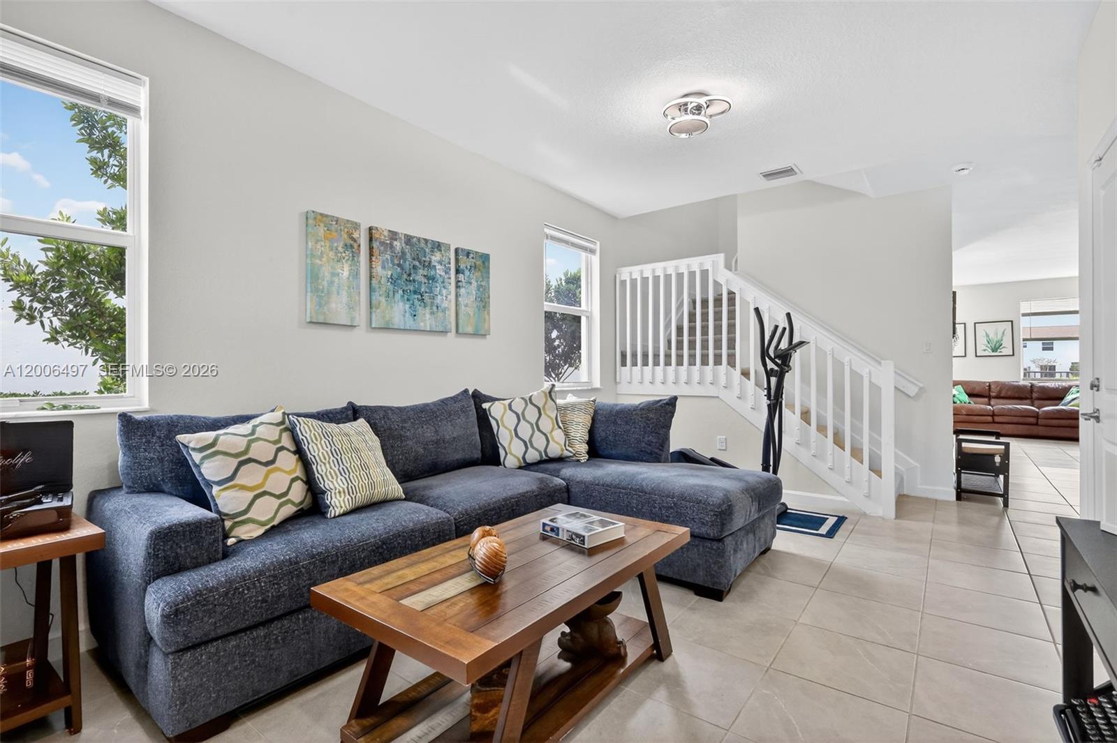 A living room features a blue sectional sofa, a wooden coffee table, and a staircase — 12936 NW 22nd Pl, Miami FL 33167, MIAMI, FL