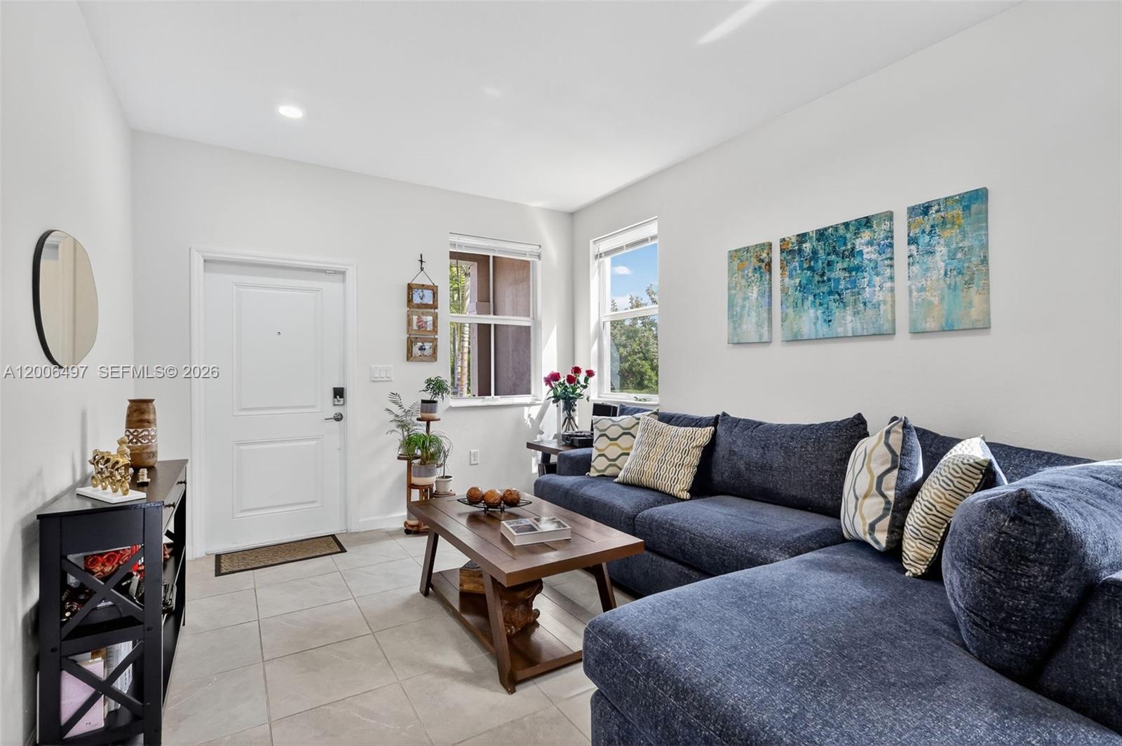 A living room features a blue sectional sofa, a wooden coffee table, and tile flooring — 12936 NW 22nd Pl, Miami FL 33167, MIAMI, FL