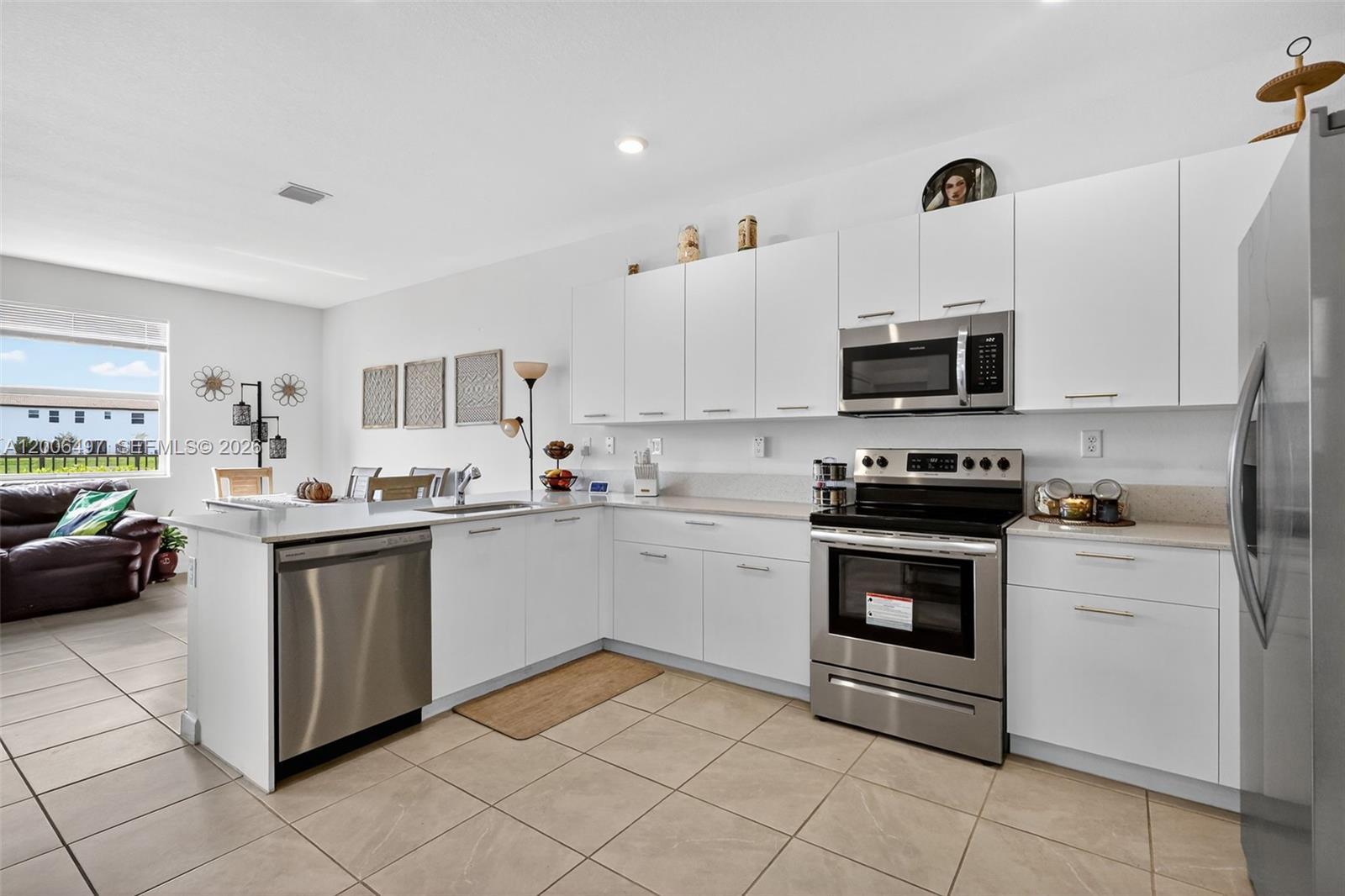A modern kitchen features white cabinets, stainless steel appliances, and tile flooring — 12936 NW 22nd Pl, Miami FL 33167, MIAMI, FL