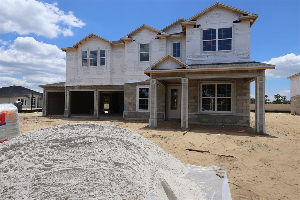 A two-story house features a three-car garage, a paved driveway, and a covered front porch — 3539 WOLVES CREEK PLACE, APOPKA, FL