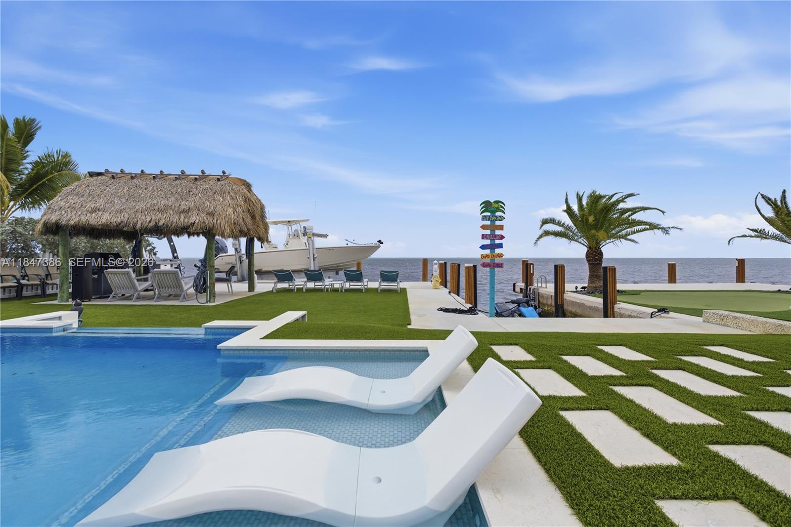 A swimming pool with lounge chairs overlooks a boat dock and the ocean — 235 Tavernier Dr, Key Largo FL 33070, KEY LARGO, FL