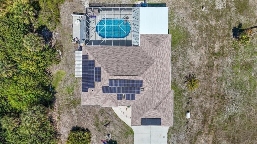 An aerial view shows a house with a screened pool and solar panels on the roof — 6993 MANNIZ ROAD, PORT CHARLOTTE, FL