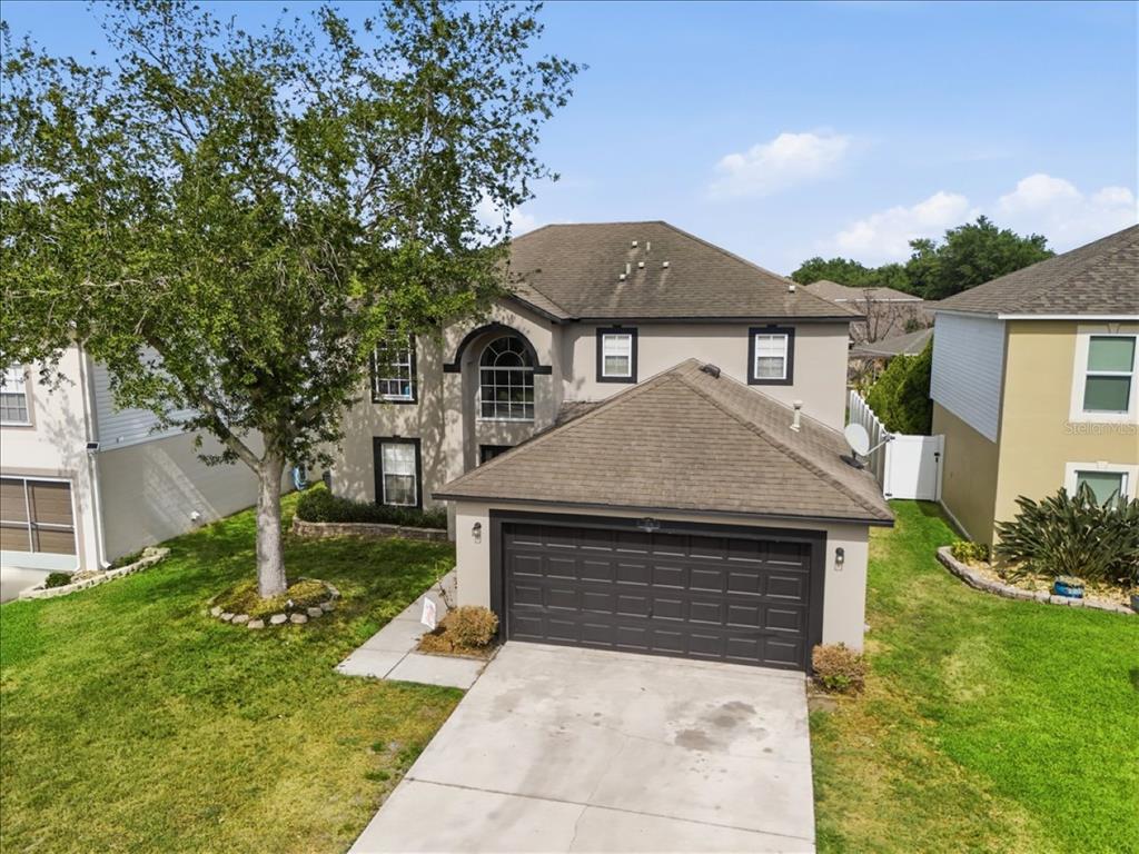 An aerial view of a two-story suburban house with a front-facing garage and driveway — 1038 MACON DRIVE, TITUSVILLE, FL