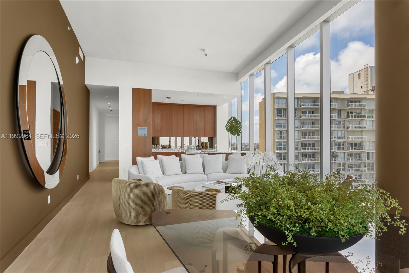 A modern living room features floor-to-ceiling windows, a white sofa, and a large oval mirror — 175 SE 25th Rd # 1501, Miami FL 33129, MIAMI, FL