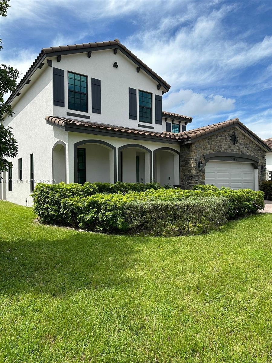 A two-story house with a stone-accented garage, arched entryway, and a manicured hedge — 3265 Dunning Dr, Royal Palm Beach FL 33411, ROYAL PALM BEACH, FL