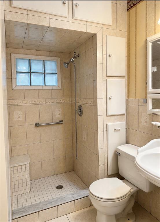 A bathroom features a tiled walk-in shower with a glass block window and a toilet — 1406 MURILLO LOOP, RUSKIN, FL