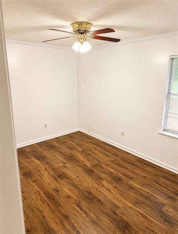 An empty bedroom features white walls, wood-look flooring, and a ceiling fan with lights — 1406 MURILLO LOOP, RUSKIN, FL