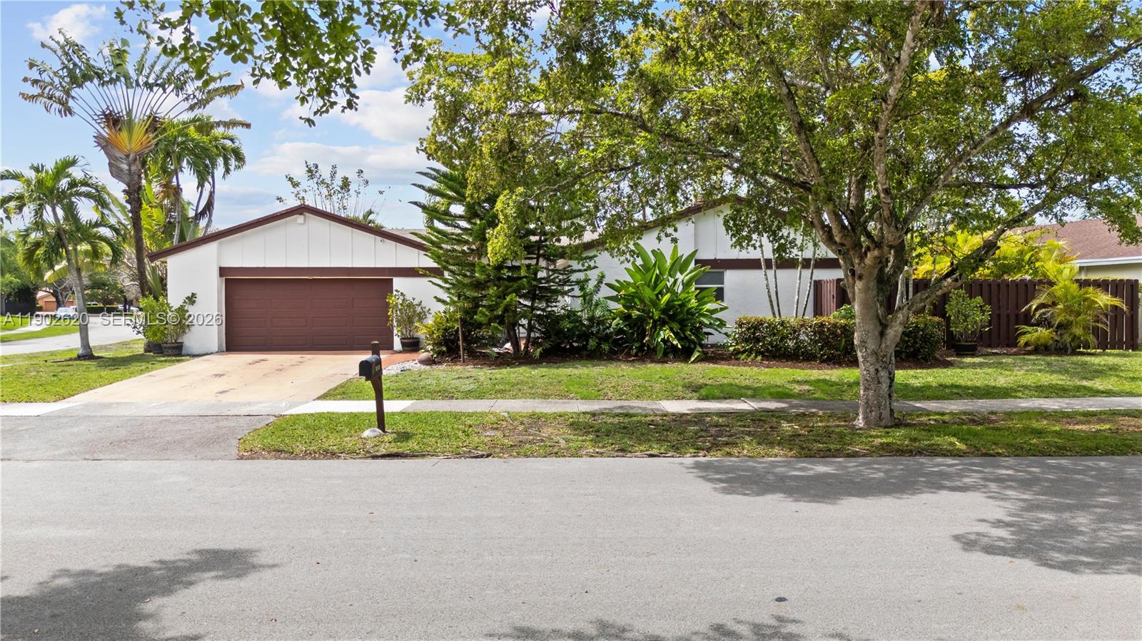 A single-story house with a brown garage door and a large tree in the yard — 10610 SW 128th Ave, Miami FL 33186, MIAMI, FL