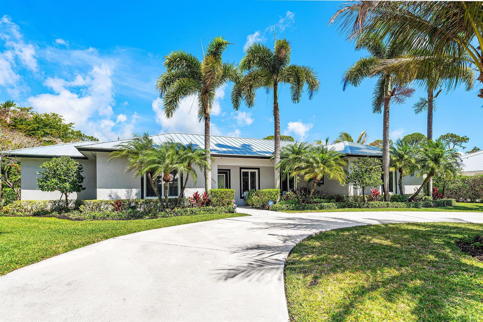 A single-story house with a metal roof, palm trees, and a curved concrete driveway — 5495 Hibiscus Road, Jupiter FL 33458, JUPITER, FL