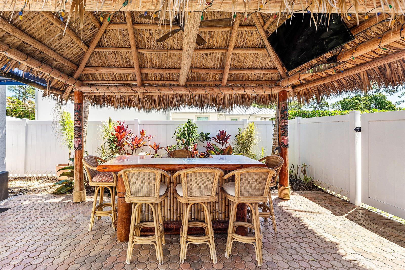 A tiki hut with a thatched roof covers a bamboo bar and wicker stools outdoors — 5495 Hibiscus Road, Jupiter FL 33458, JUPITER, FL
