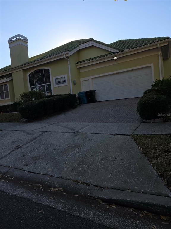 A yellow house with a green tile roof, a two-car garage, and a paved driveway — 7600 DEBEAUBIEN DRIVE, ORLANDO, FL