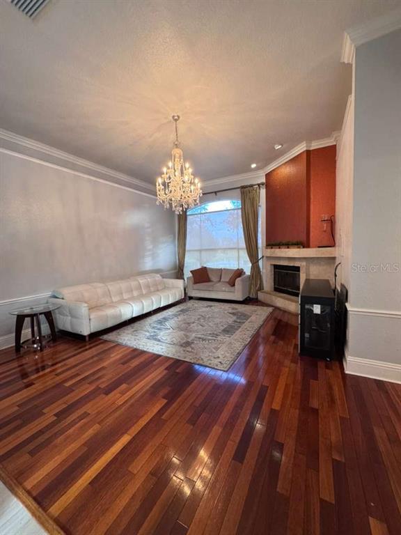 A living room features hardwood floors, a crystal chandelier, a fireplace, and two sofas — 7600 DEBEAUBIEN DRIVE, ORLANDO, FL