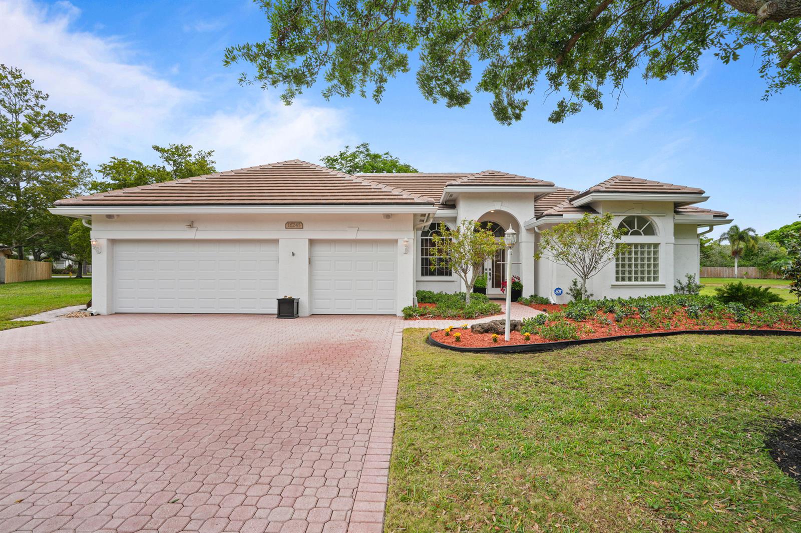 A single-story house with a tiled roof, white stucco exterior, and a paved driveway — 16245 Seneca Circle, Davie FL 33331, DAVIE, FL