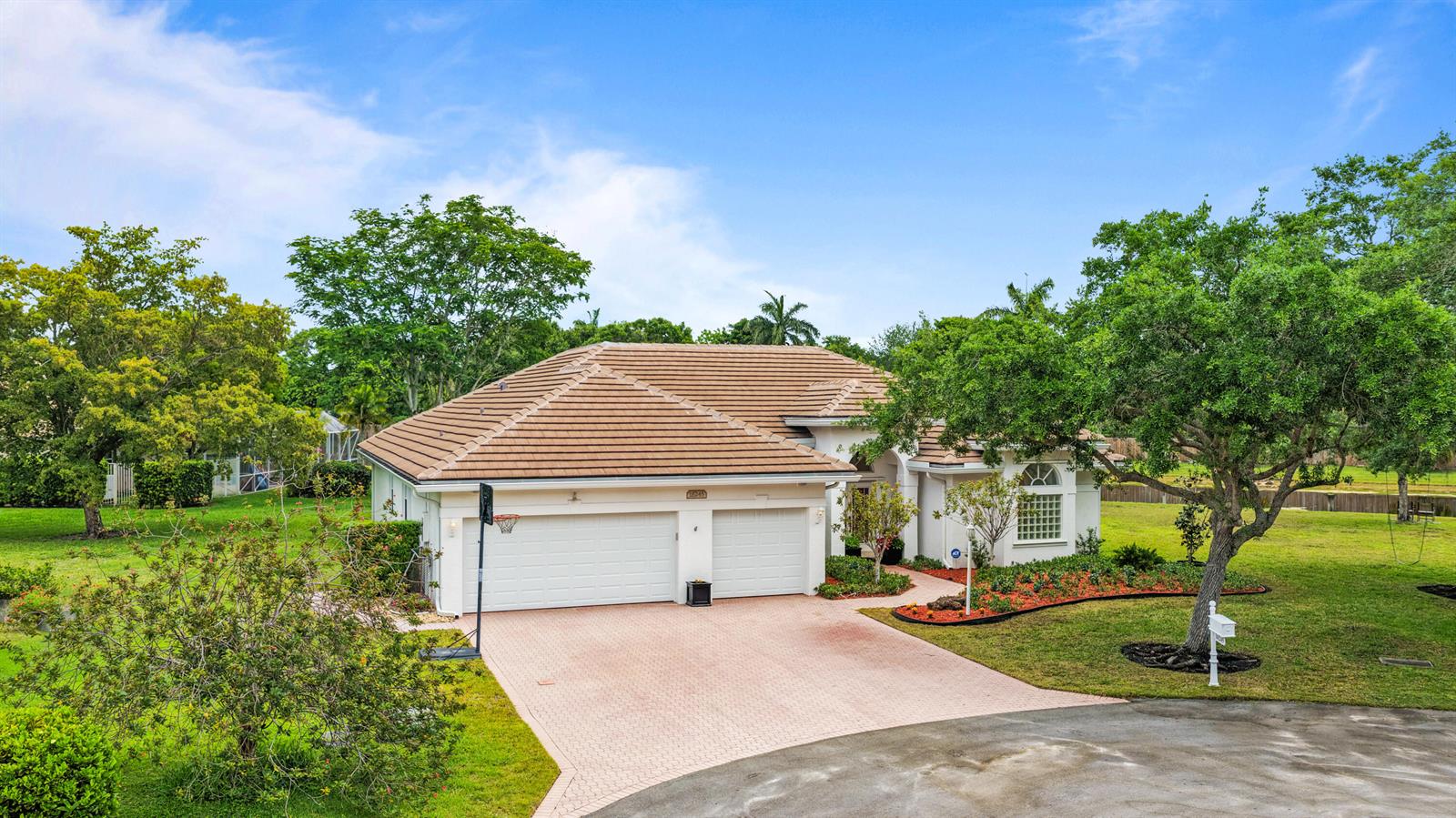 A single-story house with a tiled roof, white garage doors, and a paved driveway — 16245 Seneca Circle, Davie FL 33331, DAVIE, FL