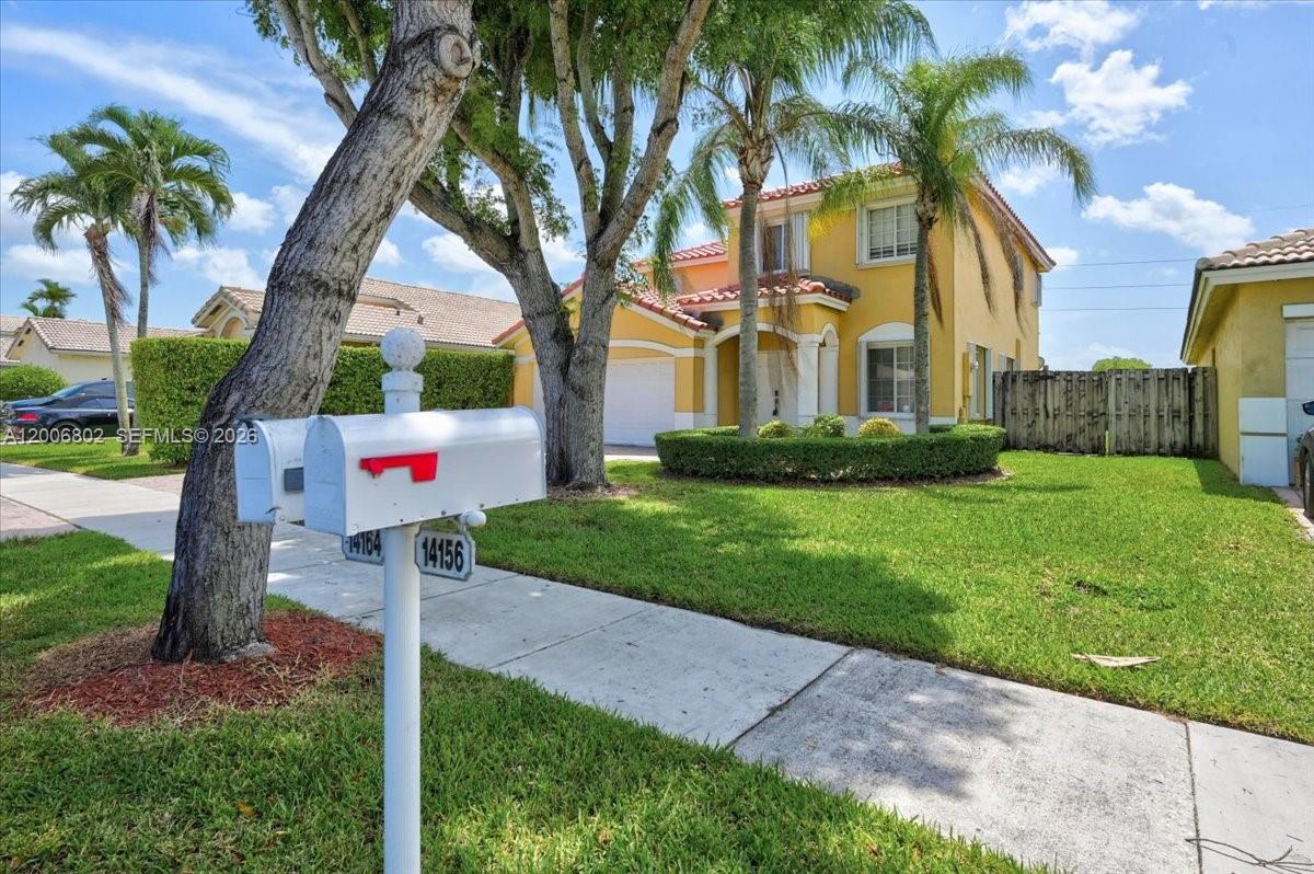 A two-story yellow house with a tile roof sits behind a mailbox and tree — 14164 SW 156th Ave, Miami FL 33196, MIAMI, FL