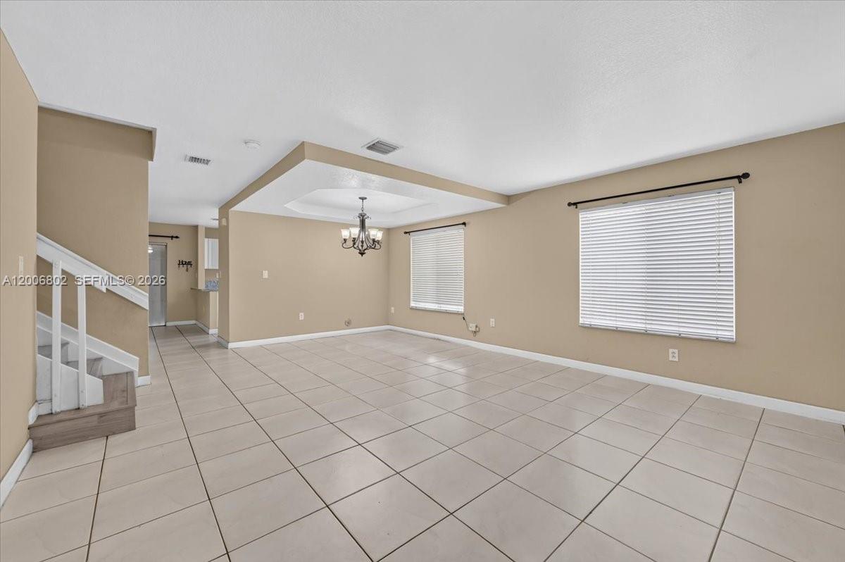 A spacious living room features beige walls, light-colored tile flooring, and a tray ceiling — 14164 SW 156th Ave, Miami FL 33196, MIAMI, FL