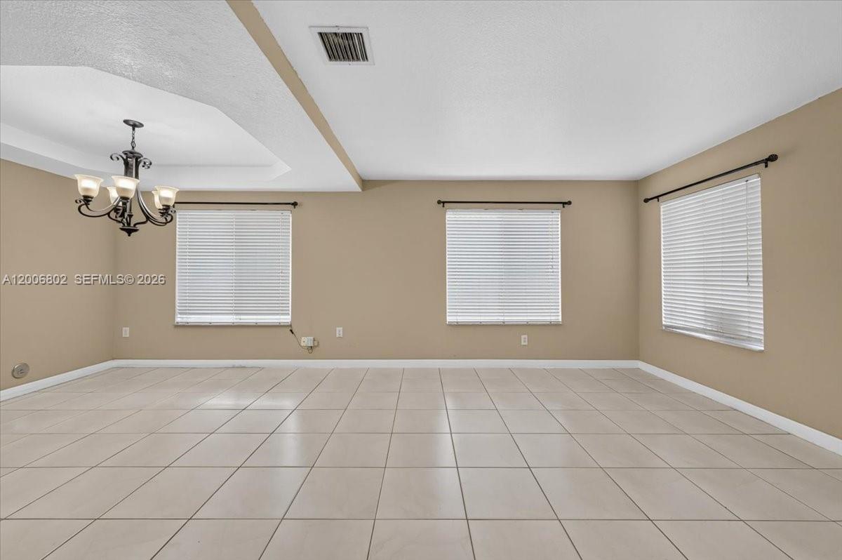 An empty room features beige walls, white tile flooring, and three windows with blinds — 14164 SW 156th Ave, Miami FL 33196, MIAMI, FL