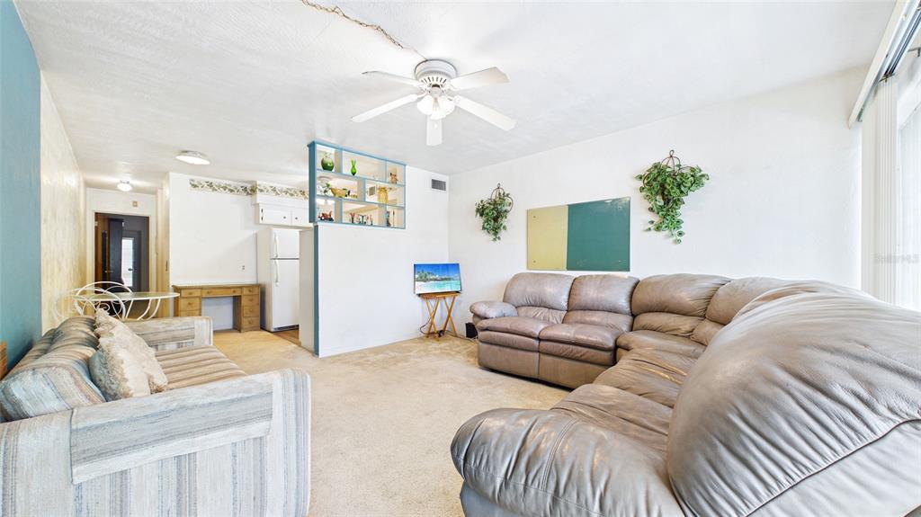 A living room features a large sectional sofa, a ceiling fan, and a room divider — 5664 40TH TERRACE N UNIT 428, ST PETERSBURG, FL