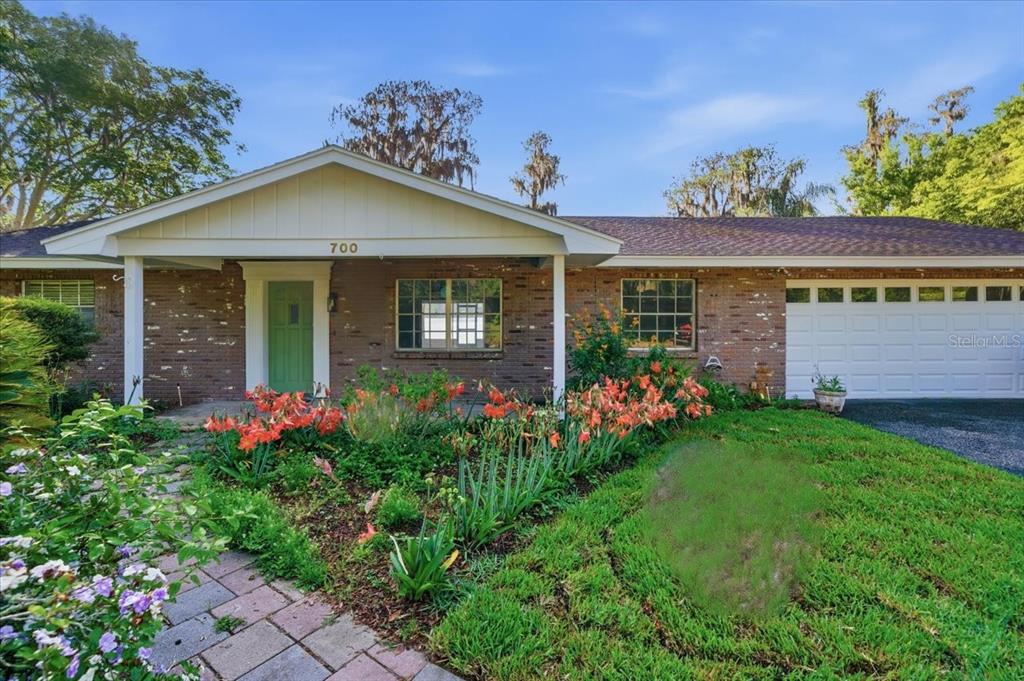 A single-story brick house with a green front door and an attached two-car garage — 700 DRUID WAY, LUTZ, FL