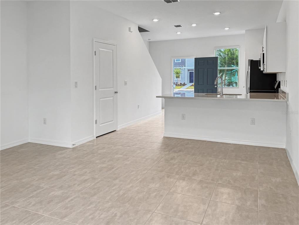 An open-concept kitchen and living area features light tile flooring and a breakfast bar — 2949 SKYLINE LOOP, KISSIMMEE, FL