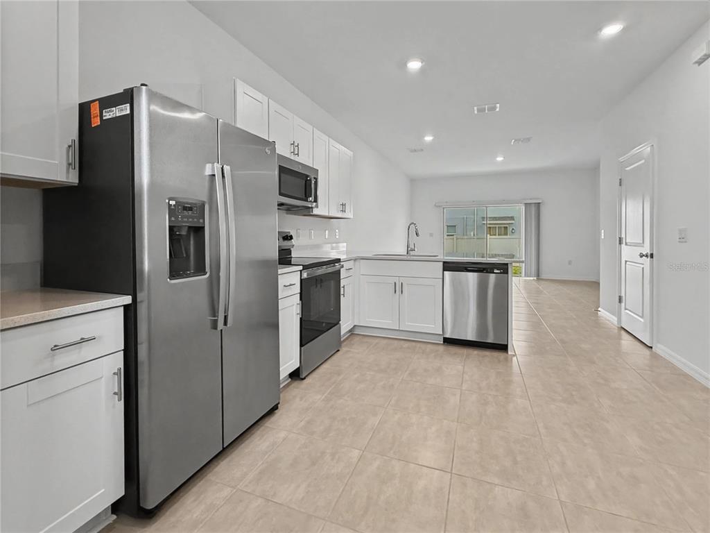 A kitchen with white cabinets, stainless steel appliances, and light-colored tile flooring — 2949 SKYLINE LOOP, KISSIMMEE, FL