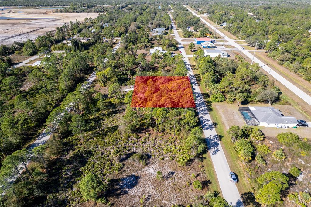 An aerial view shows a rectangular plot of land highlighted in red among wooded surroundings — 26335 GLASPELL ROAD, PUNTA GORDA, FL