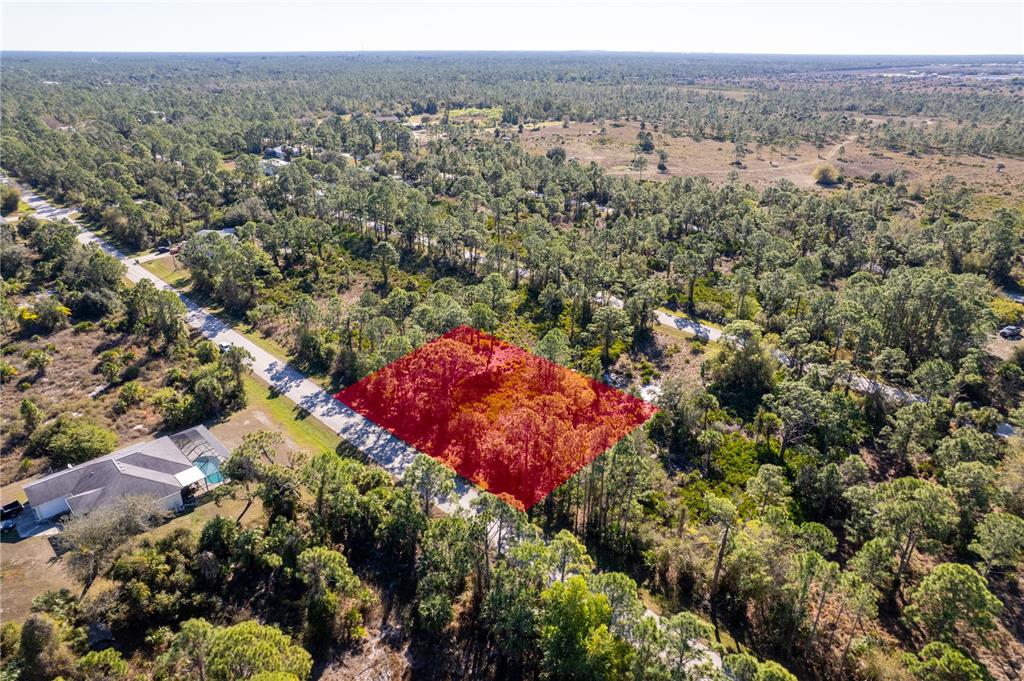 An aerial view shows a rectangular, wooded lot highlighted in red along a paved road — 26335 GLASPELL ROAD, PUNTA GORDA, FL