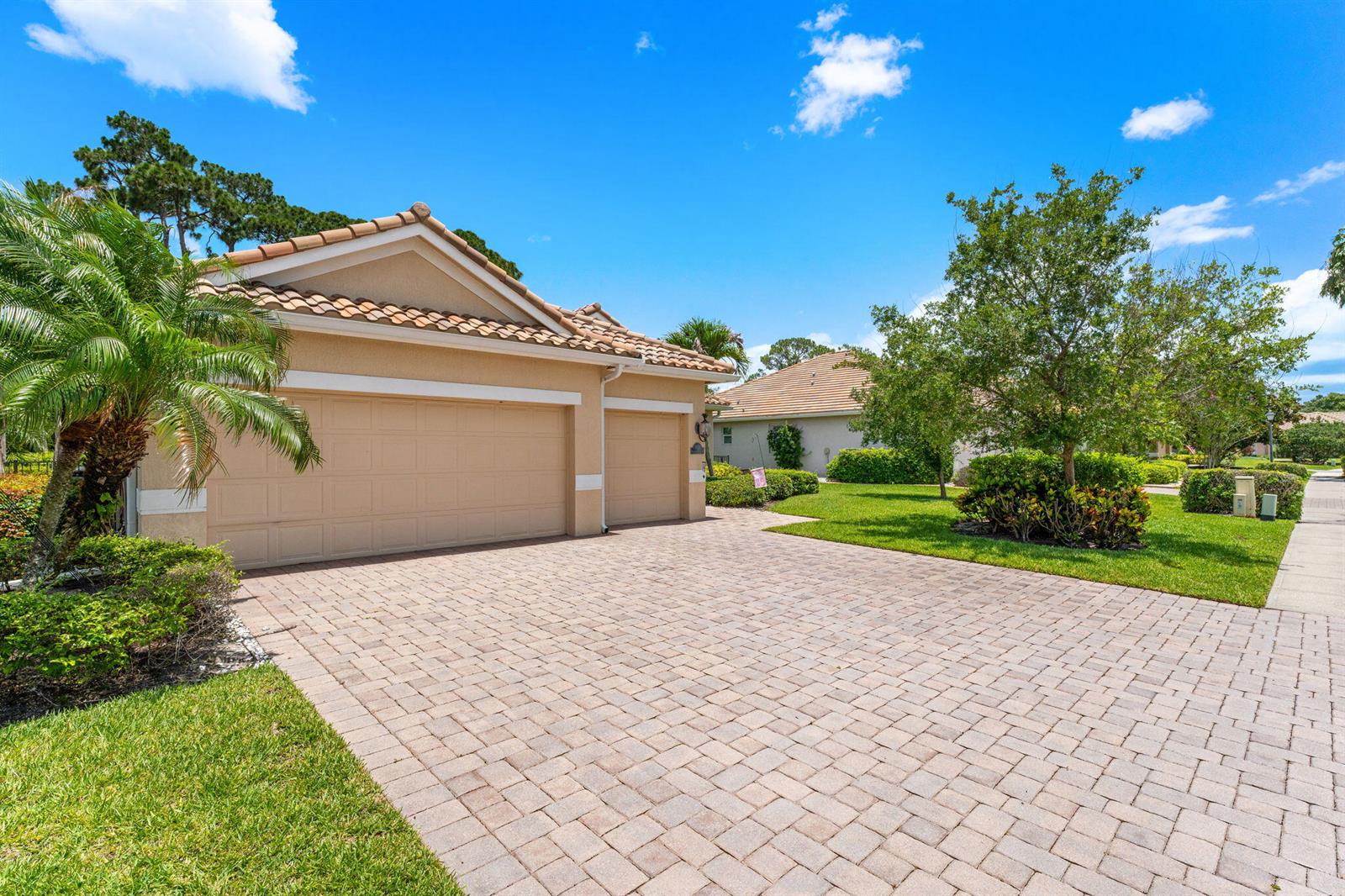 A beige house with a tiled roof and a brick paver driveway under a blue sky — 7657 Fieldstone Ranch Square, Vero Beach FL 32967, VERO BEACH, FL