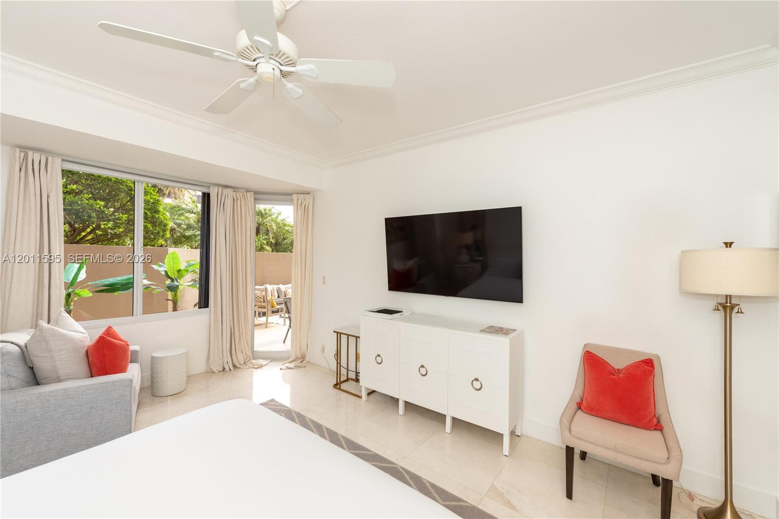 A bedroom features a wall-mounted television, a white media console, and a sliding glass door — 201 Crandon Blvd # 138, Key Biscayne FL 33149, KEY BISCAYNE, FL
