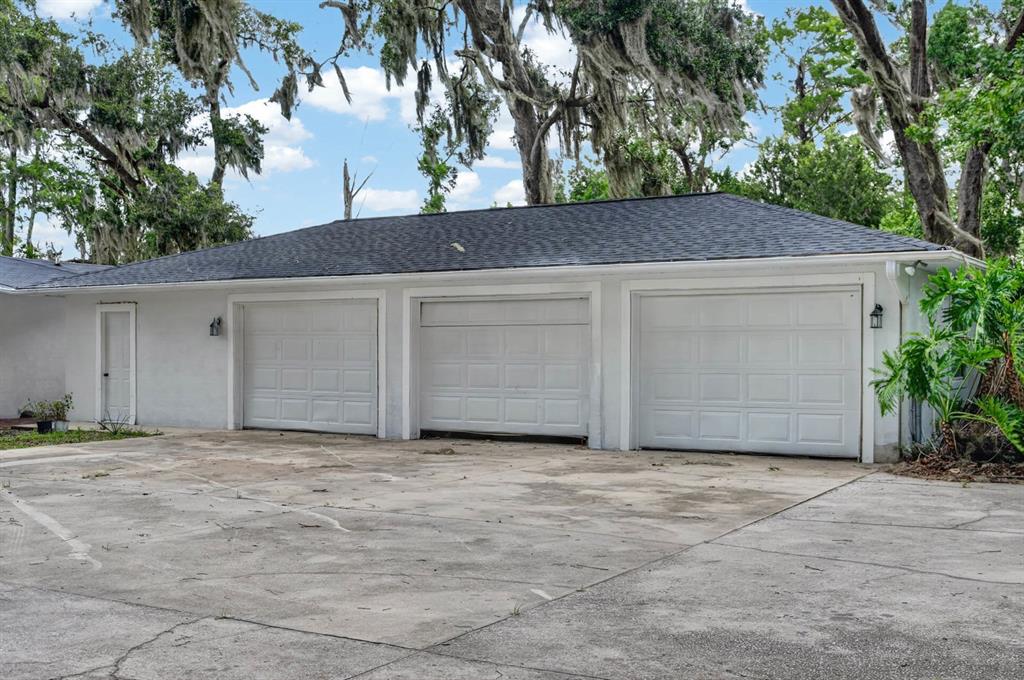 A detached three-car garage with white walls and a dark shingled roof sits outdoors — 157 W GRANDVIEW DRIVE, EAST PALATKA, FL