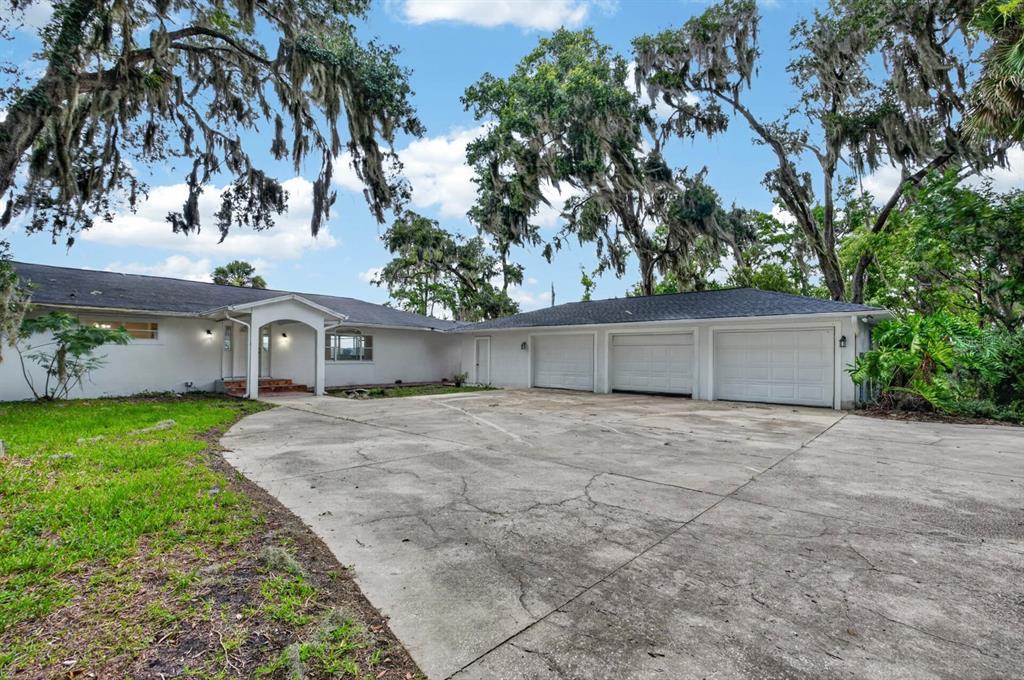 A white single-story house with a three-car garage and a large concrete driveway — 157 W GRANDVIEW DRIVE, EAST PALATKA, FL