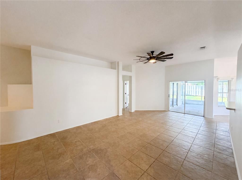 An open living area features tile flooring, a ceiling fan, and sliding glass doors — 4532 PERDITA LANE, LUTZ, FL