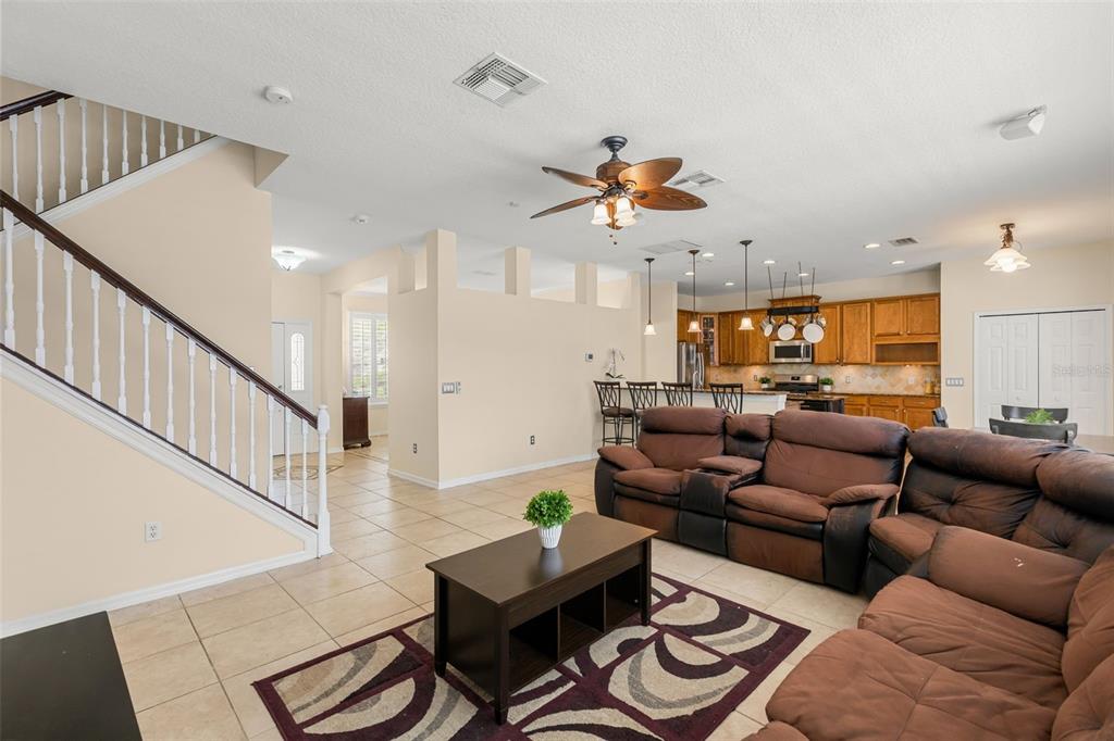 An open-concept living room with tile floors, a staircase, and a kitchen in the background — 1573 ANNA CATHERINE DRIVE, ORLANDO, FL