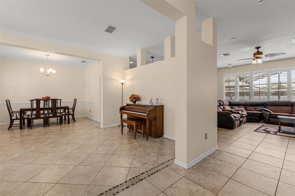 An open-concept living and dining area features tile flooring, a piano, and a leather sectional — 1573 ANNA CATHERINE DRIVE, ORLANDO, FL