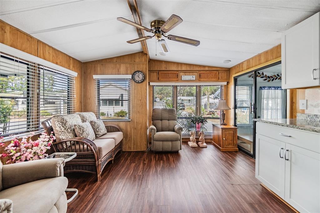 A sunroom features wood-paneled walls, a ceiling fan, a sofa, a recliner, and vinyl flooring — 39334 MAHER DRIVE, ZEPHYRHILLS, FL