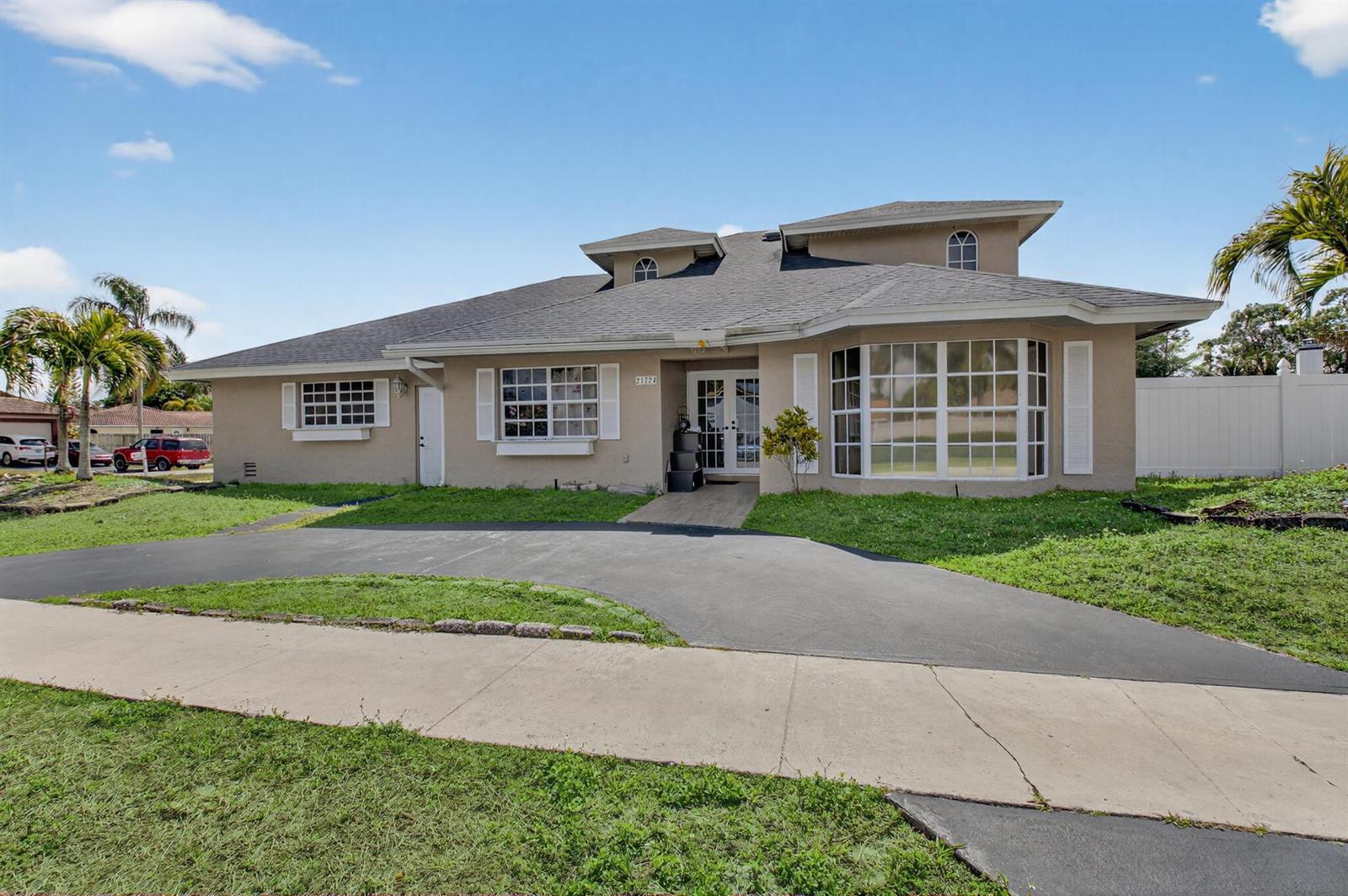 A single-story beige house with a dark shingled roof and a curved driveway — 21724 Little Bear Way, Boca Raton FL 33428, BOCA RATON, FL