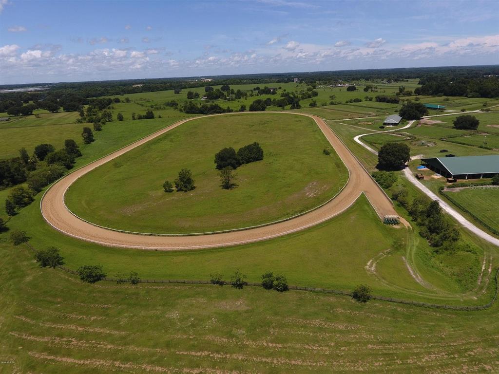 An aerial view of a rural property featuring a dirt horse training track and barns — 12020 N US HIGHWAY 441, OCALA, FL