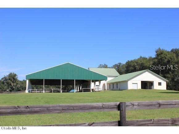 A large green-roofed barn and an adjacent white building sit on a grassy field — 12020 N US HIGHWAY 441, OCALA, FL