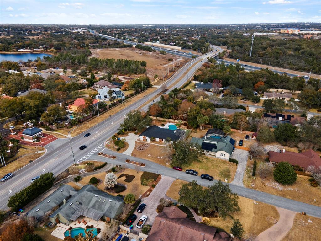 An aerial view shows several houses with pools near a highway and a lake — 7337 BRANCHTREE DRIVE, ORLANDO, FL