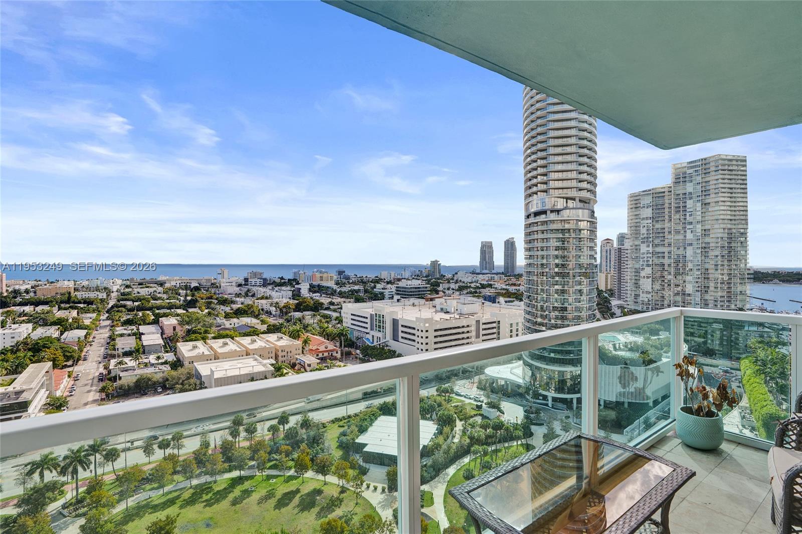 A high-rise balcony overlooks a city park, surrounding buildings, and the distant ocean — 650 West Ave # 2206, Miami Beach FL 33139, MIAMI BEACH, FL