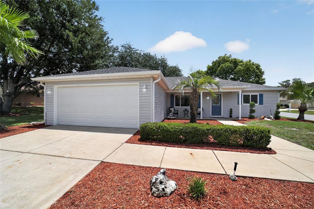 A single-story house with light gray siding, a two-car garage, and a front porch — 13685 SE 90TH COURT, SUMMERFIELD, FL