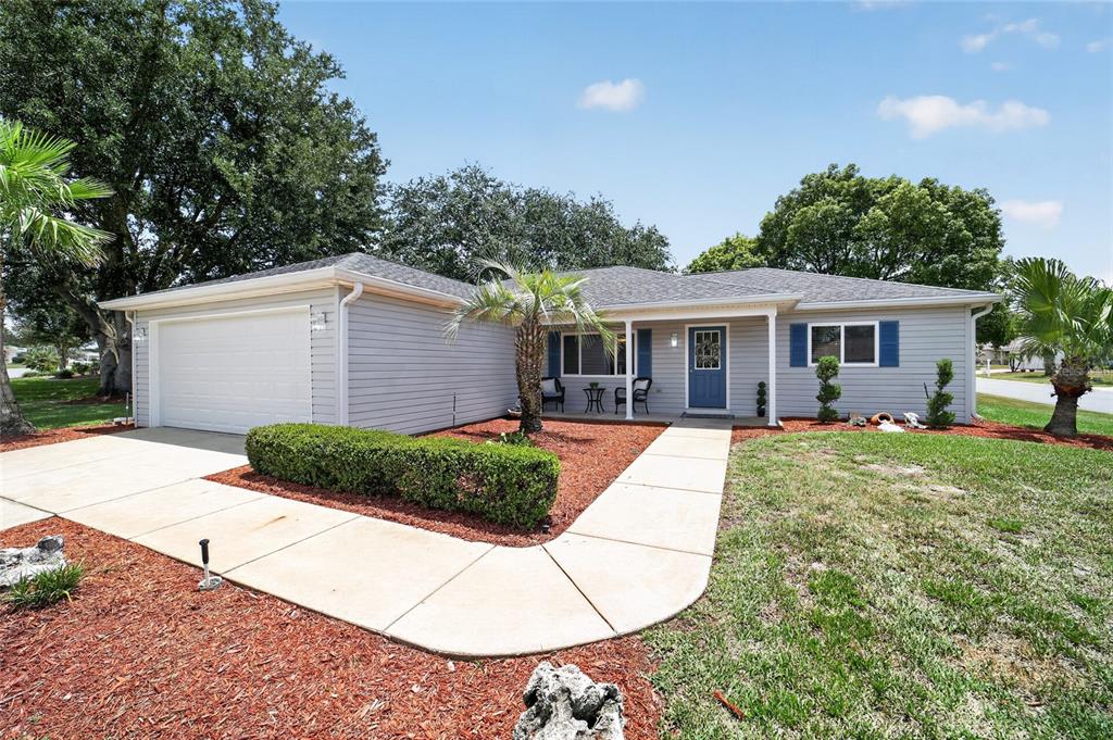 A single-story house with gray siding, a white garage door, and a blue front door — 13685 SE 90TH COURT, SUMMERFIELD, FL