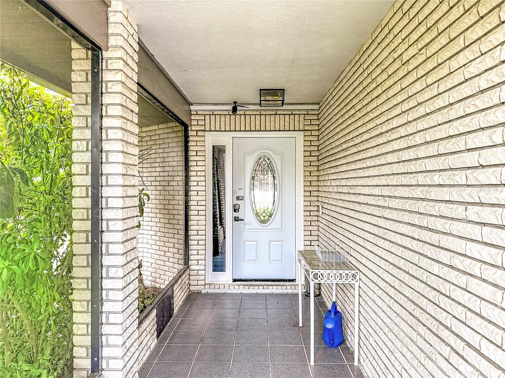 A covered brick entryway features a white front door with a glass oval insert — 1654 SE FALLON DRIVE, PORT ST LUCIE, FL