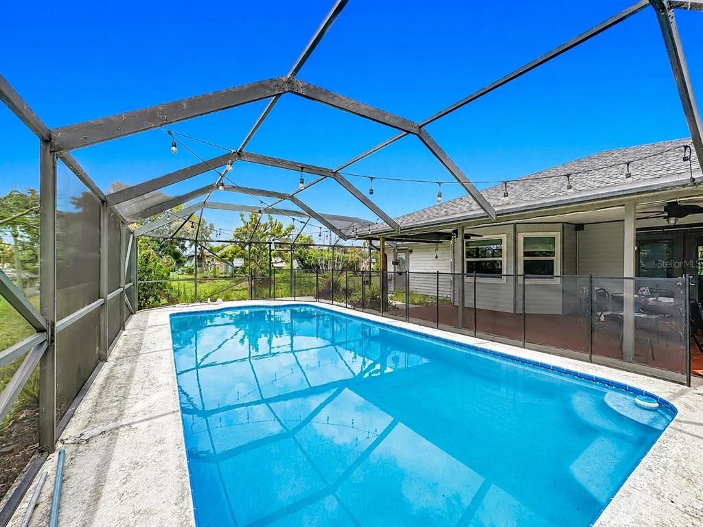 A swimming pool is enclosed by a screened lanai with a patio and safety fence — 1654 SE FALLON DRIVE, PORT ST LUCIE, FL