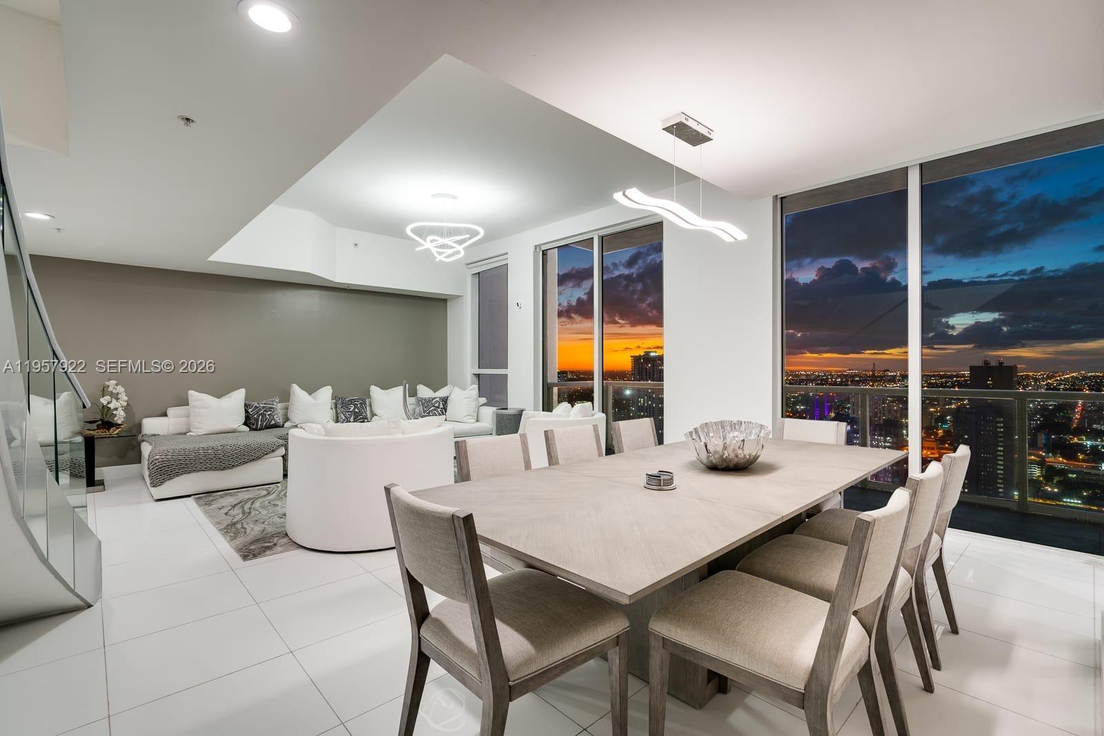 A modern dining and living area features white tile floors, contemporary lighting, and floor-to-ceiling windows — 253 NE 2nd St # 4904, Miami FL 33132, MIAMI, FL