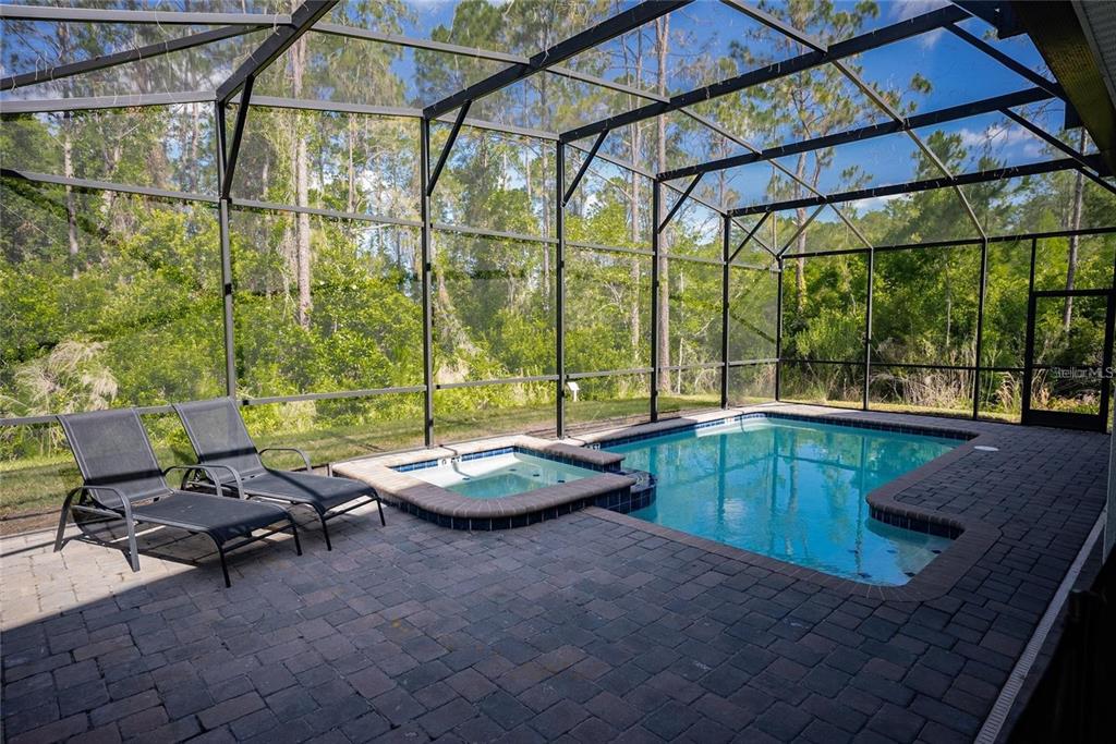 A screened-in patio features a swimming pool, a raised spa, and two lounge chairs — 2701 BOOKMARK DRIVE, KISSIMMEE, FL