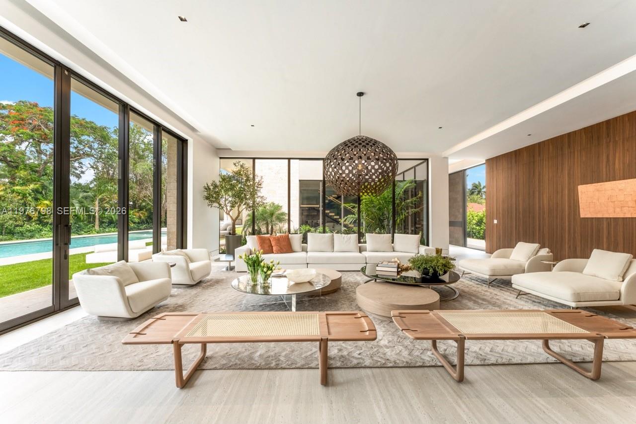 A spacious modern living room features floor-to-ceiling windows, a large sectional, and wood paneling — 8755 SW 54th Ave, Miami FL 33143, MIAMI, FL