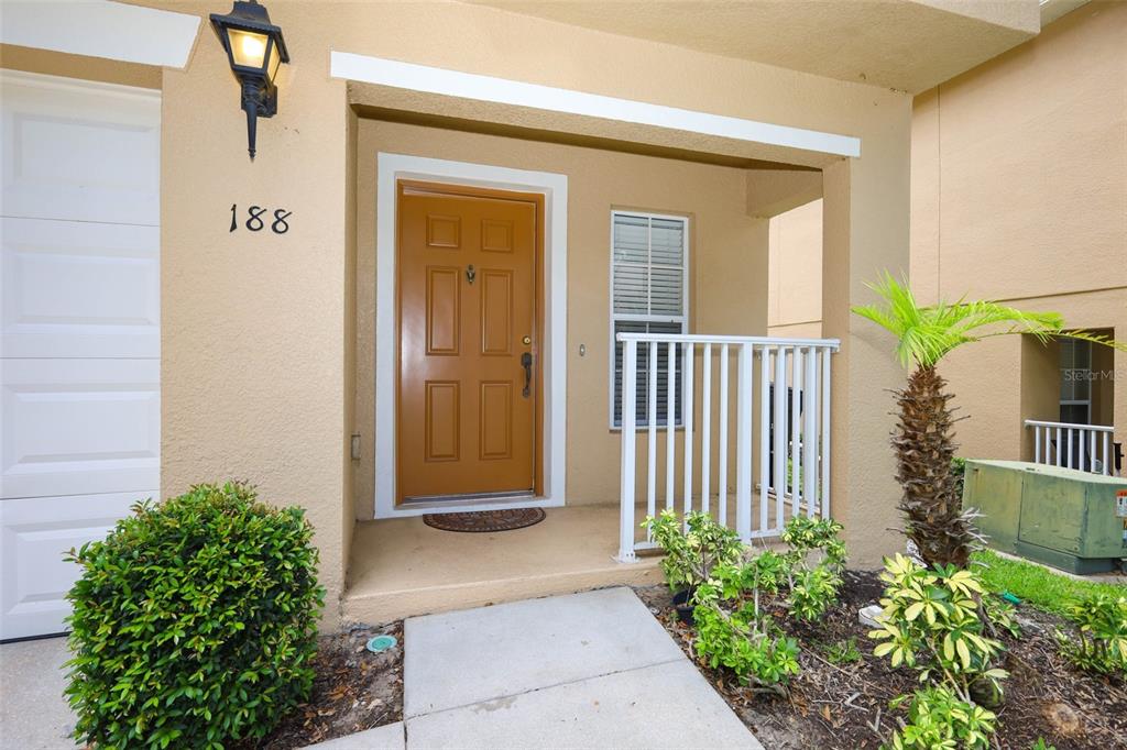 The exterior of a home entrance features a tan stucco wall, brown door, and walkway — 188 STERLING SPRINGS LANE, ALTAMONTE SPRINGS, FL