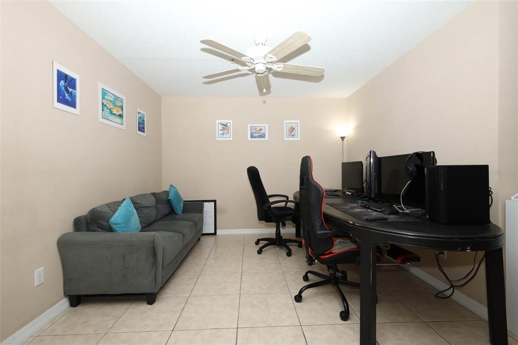 A room with tile flooring, a gray sofa, and a long desk with two gaming chairs — 188 STERLING SPRINGS LANE, ALTAMONTE SPRINGS, FL